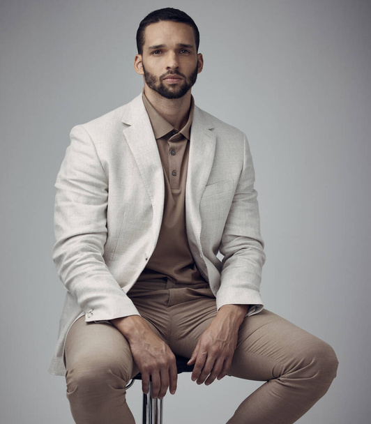 A well-tailored suit provides unlimited confidence. Shot of a handsome young man sitting alone in the studio during the day. - Zdjęcie, obraz