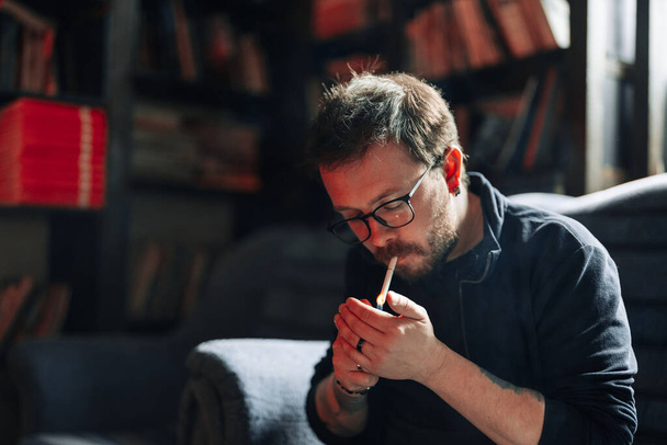 Smoking Man portrait with books in background - Photo, Image