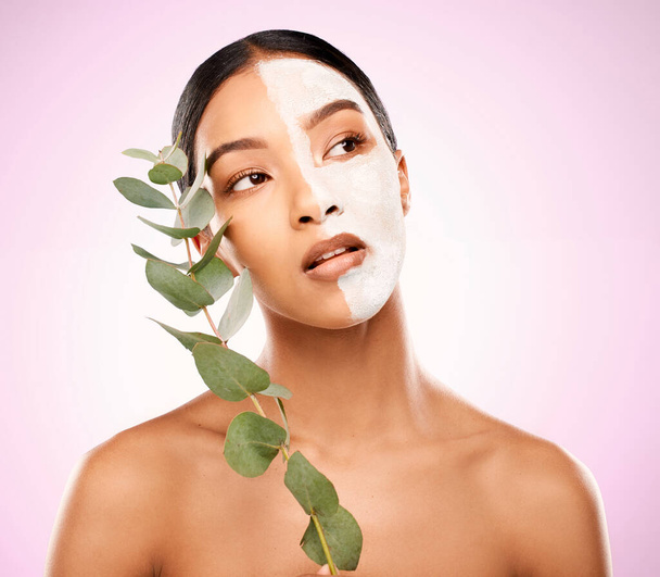Have a pamper day the organic way. Studio shot of an attractive young woman holding a plant and having a facial against a pink background. - Foto, Bild