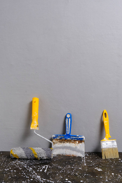 Paint roller, brush and spatula on a gray wall background, repair tool - 写真・画像