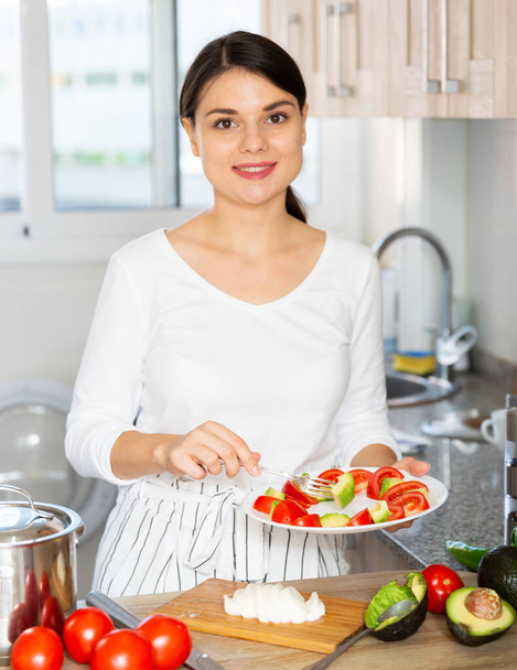 Woman tasting vegetable salad in kitchen - Photo, Image