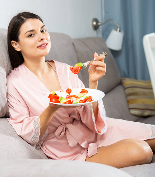 Donna che mangia insalata sul divano - Foto, immagini