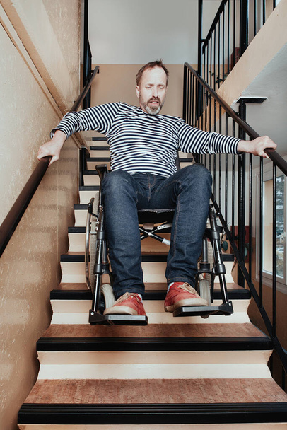Disabled man on wheel chair riding down the stairs - 写真・画像