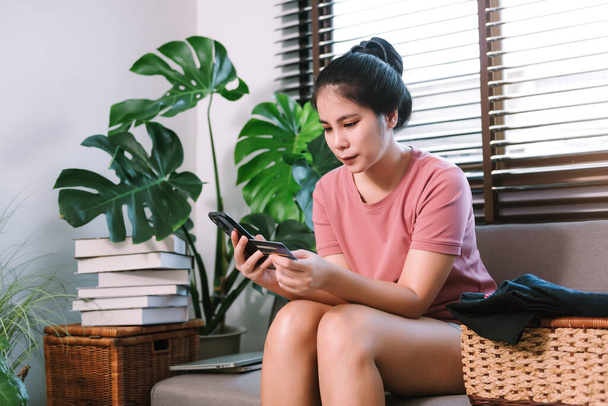 Азиатская молодая женщина домохозяйка, использующая смартфон для покупок в Интернете и оплаты кредитной картой для покупки оборудования по дому. - Фото, изображение