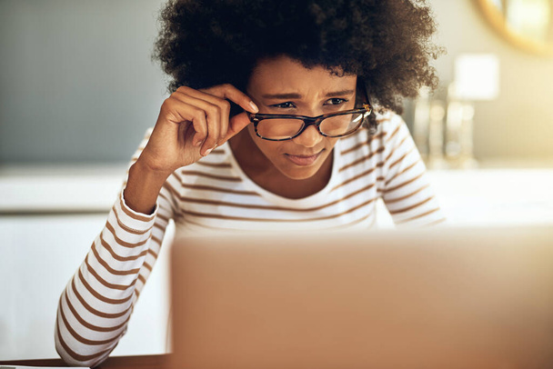 Čtu to správně. Snímek soustředěné mladé ženy pracující na svém notebooku, zatímco drží její brýle na čtení doma během dne. - Fotografie, Obrázek