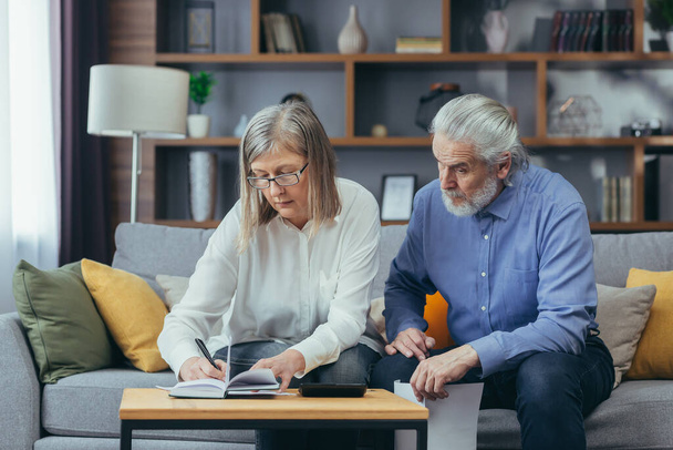 gray hair mature senior couple counting money and calculating finances while preparing tax report at home Older family with payment domestic bill checking financial documents, planning budget together - Фото, зображення