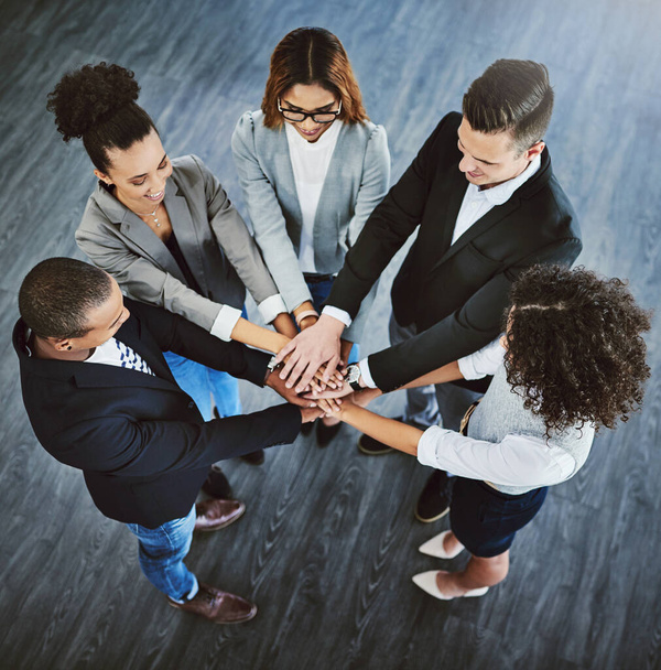 Teamwork trumps it all. High angle shot of a group of businesspeople joining their hands together in a huddle. - Foto, immagini