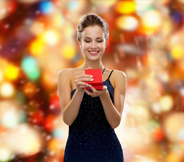 Hymyilevä nainen, jolla on punainen lahjapakkaus
 - Valokuva, kuva