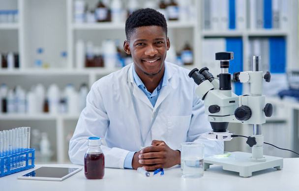 Its been a long productive day. Portrait of a cheerful young male scientist standing at his desk inside of a laboratory during the day. - Photo, Image