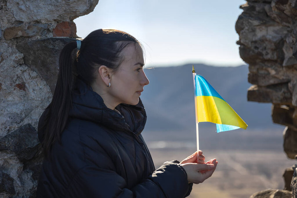 Uma jovem mulher com a bandeira da Ucrânia em suas mãos. - Foto, Imagem