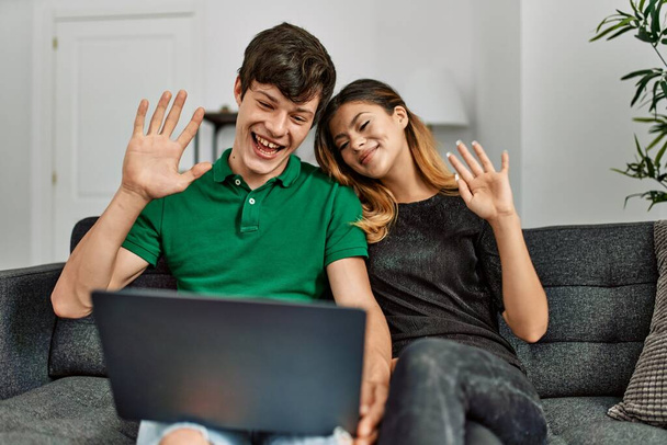 Jeune couple caucasien souriant heureux ayant appel vidéo à l'aide d'un ordinateur portable à la maison. - Photo, image