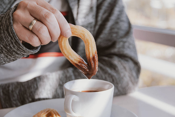 close-up of a man eating a typical sweet Spanish breakfast and churros with chocolate - Φωτογραφία, εικόνα