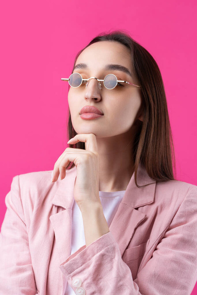 Portrait of beautiful young woman in pink jacket thinking isolated on red background - Foto, Imagen