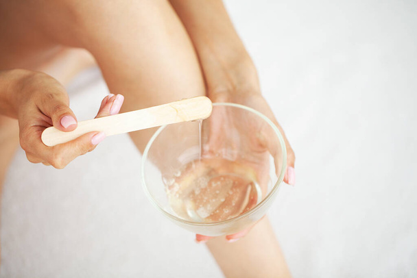Young woman depilating legs with liquid sugar at home - Photo, Image