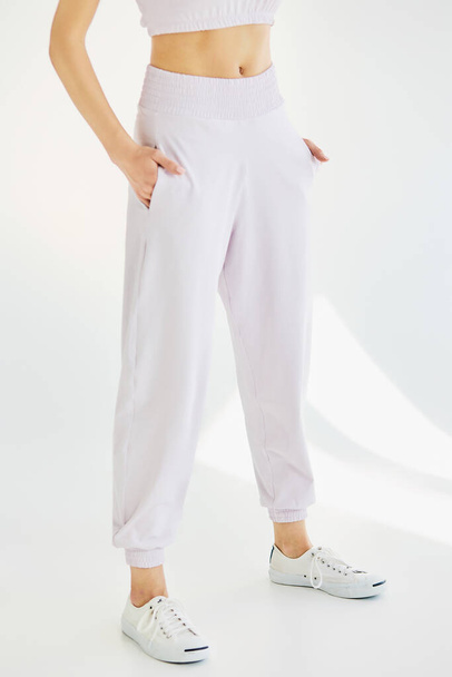 A young girl in pink sweatpants on a white background - Фото, изображение
