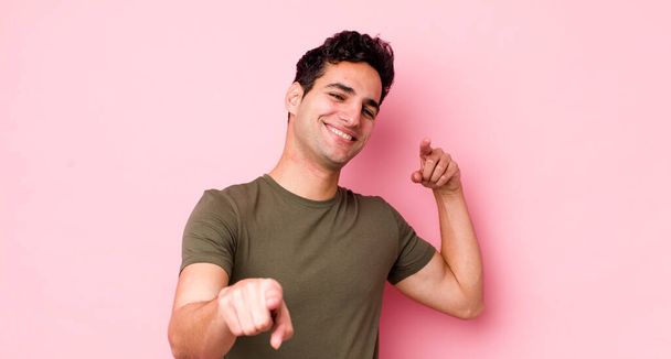 handsome hispanic man feeling happy and confident, pointing to camera with both hands and laughing, choosing you - Valokuva, kuva