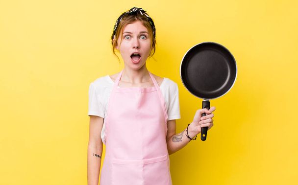 red head pretty woman looking very shocked or surprised. fry pan and housewife concept - Fotoğraf, Görsel