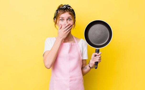 red head pretty woman covering mouth with hands with a shocked. fry pan and housewife concept - Foto, immagini