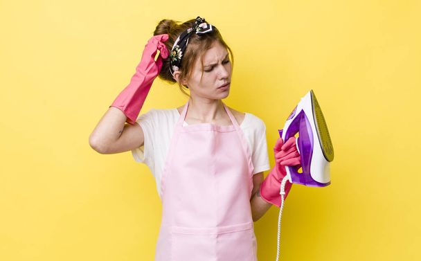 red head pretty woman feeling puzzled and confused, scratching head. housekeeper concept - 写真・画像