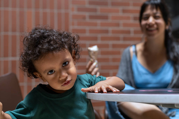 Mom and her Latin American son sharing an ice cream. Motherhood and Mother's Day concept. - Fotografie, Obrázek