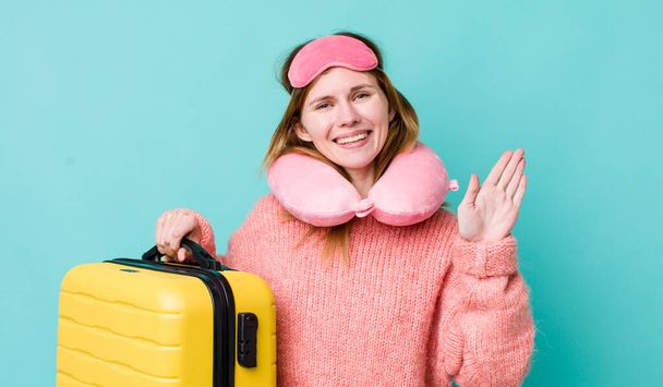 red head pretty woman smiling happily, waving hand, welcoming and greeting you. flight passenger concept - Foto, Bild