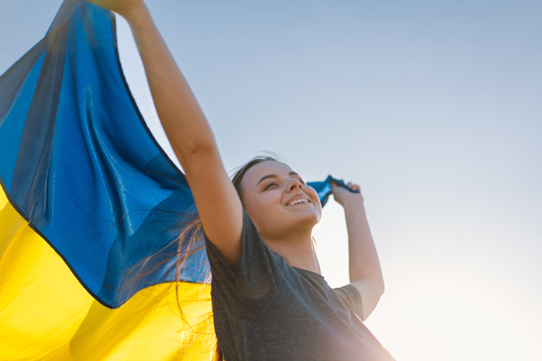 Femme tenant un drapeau jaune et bleu de l'Ukraine en plein air - Photo, image