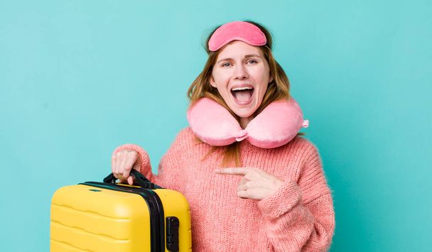 red head pretty woman looking excited and surprised pointing to the side. flight passenger concept - 写真・画像