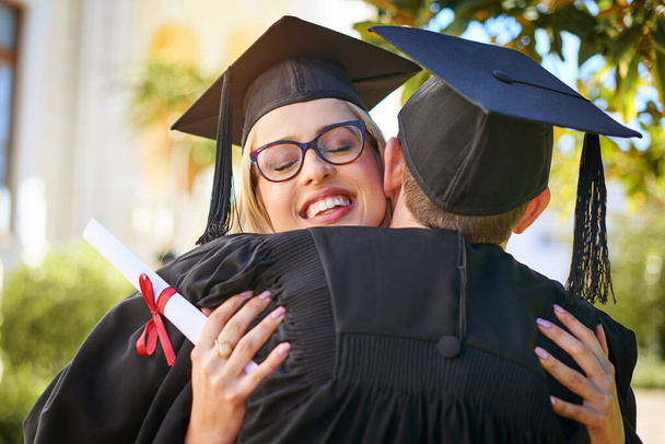 Celebrating our big accomplishment. Shot of a young couple embracing each other on graduation day. - Фото, изображение