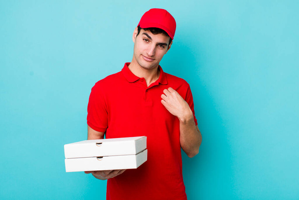 handsome hispanic man looking arrogant, successful, positive and proud. delivery pizza concept - Фото, изображение