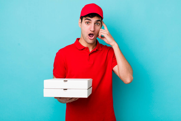 handsome hispanic man looking surprised, realizing a new thought, idea or concept. delivery pizza concept - Foto, Bild