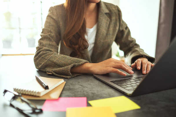 Podnikatelka pomocí a psaní na notebooku s papírováním na stole v kanceláři - Fotografie, Obrázek