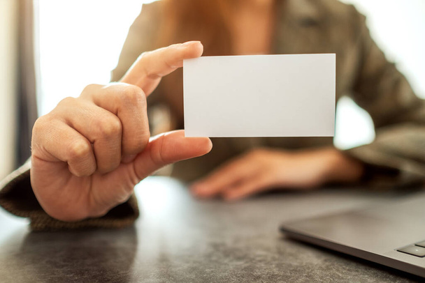 Деловая женщина держит и показывает пустые визитки в офисе - Фото, изображение