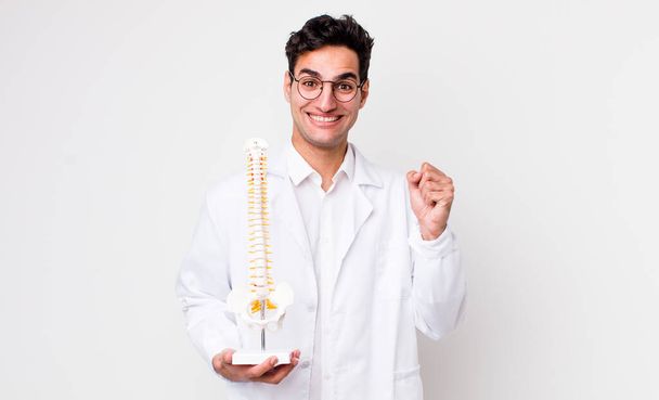 handsome hispanic man feeling shocked,laughing and celebrating success. spine specialist concept - Φωτογραφία, εικόνα
