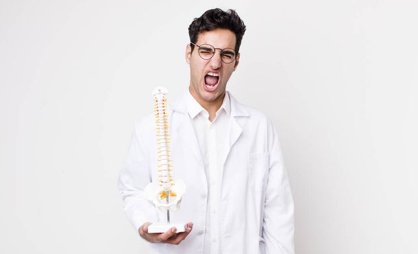 handsome hispanic man shouting aggressively, looking very angry. spine specialist concept - Foto, afbeelding