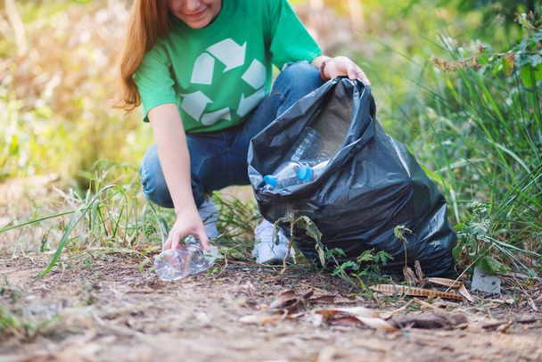 Lähikuva kuva nainen poimien roskat muovipullot muovipussiin kierrätykseen käsite - Valokuva, kuva