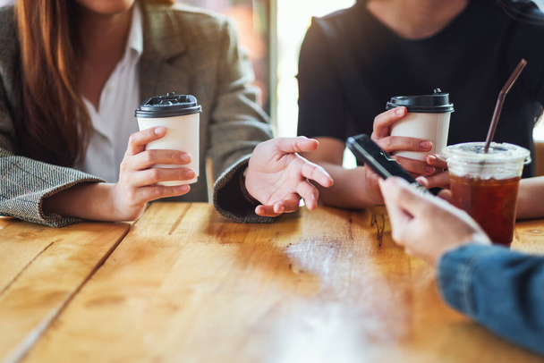 Closeup image of people using mobile phone and drinking coffee together - Photo, Image