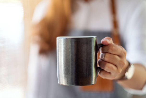 Una cameriera che tiene e serve una tazza di caffè caldo nel caffè - Foto, immagini
