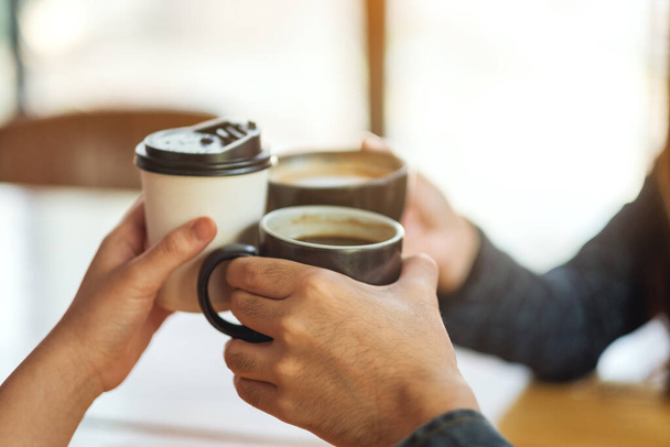 Zbliżenie obraz osób lubiących pić i brzęczenie filiżanek kawy na stole w kawiarni - Zdjęcie, obraz