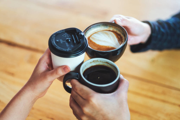 Immagine primo piano di persone goduto di bere e clinking tazze di caffè sul tavolo in caffè - Foto, immagini