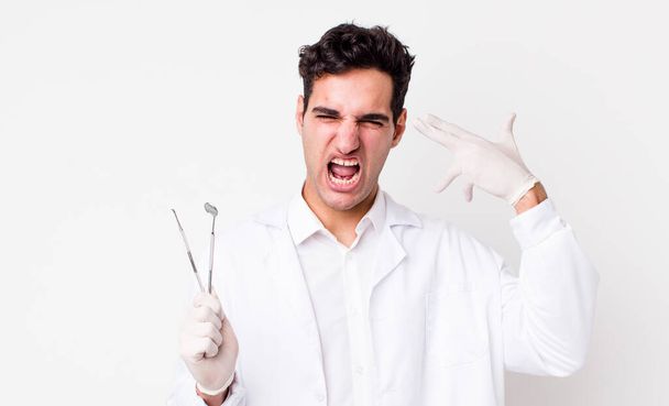 handsome hispanic man looking unhappy and stressed, suicide gesture making gun sign. dentist concept - Foto, Imagem