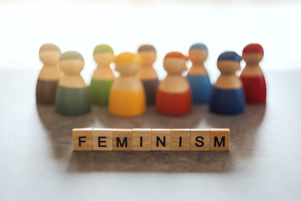 FEMINISMO palabra en bloques de madera con un grupo de mujeres en el fondo - Foto, imagen