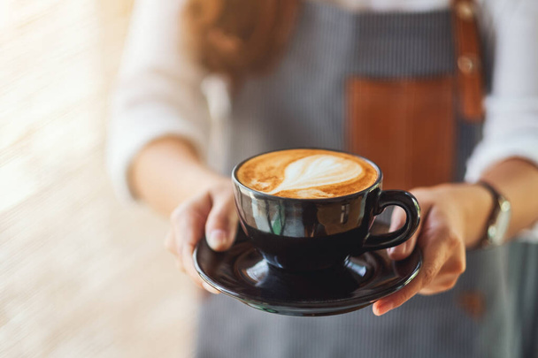 Eine Kellnerin hält und serviert eine Tasse heißen Kaffee im Café - Foto, Bild