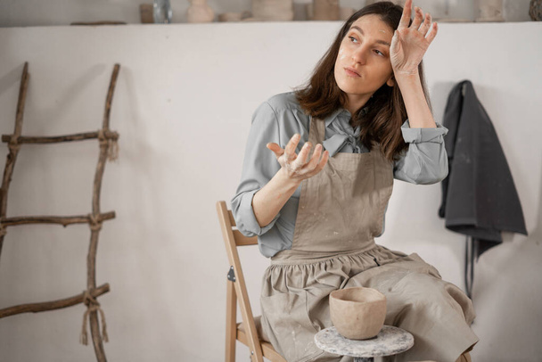 Unavený kavkazský krásný ženský hrnčíř na pracovišti. vytvoření ručně vyráběné keramiky. hrnčíř v keramickém studiu tvoří hrnec z mokré hlíny. Ženský tvrdě pracující koncept. kopírovat prostor. - Fotografie, Obrázek