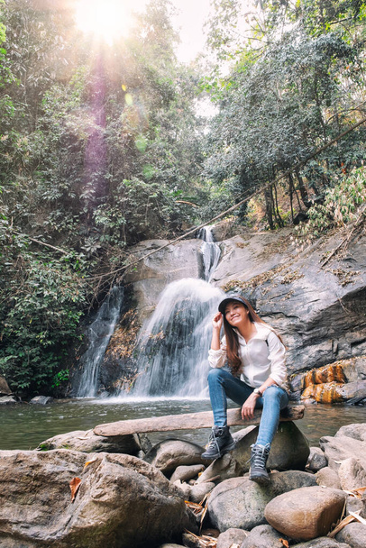 Красива азіатська жінка сидить перед водоспадом у джунглях
 - Фото, зображення