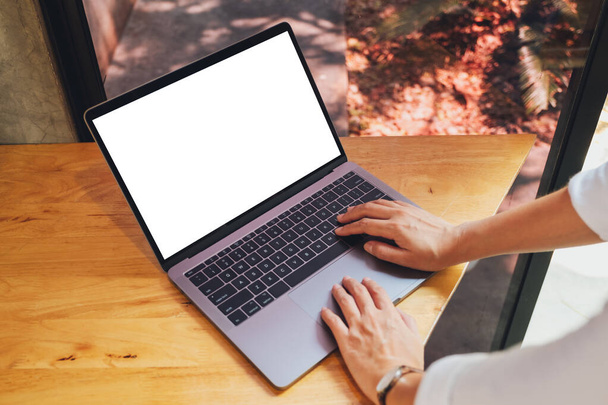 Top view makieta obrazu kobiety za pomocą i wpisując na laptopie z pustym białym ekranem pulpitu na drewnianym stole - Zdjęcie, obraz