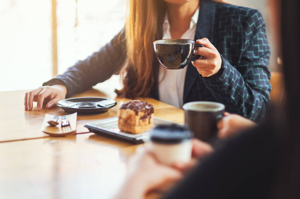 Κοντινή εικόνα των ανθρώπων που απολαμβάνουν να μιλούν, να τρώνε και να πίνουν καφέ μαζί στο καφέ - Φωτογραφία, εικόνα