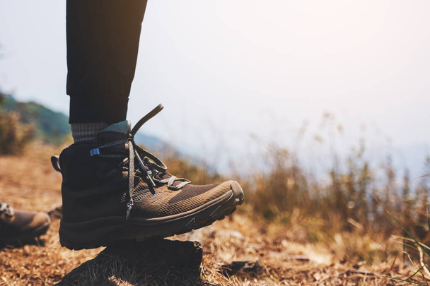 Closeup image of a woman's legs with trekking boots on the top of mountain - Photo, Image
