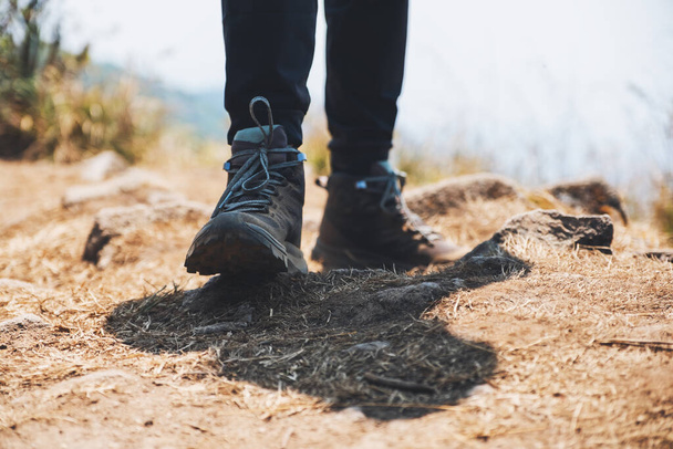 Closeup image of a woman's legs with trekking boots on the top of mountain - Photo, Image