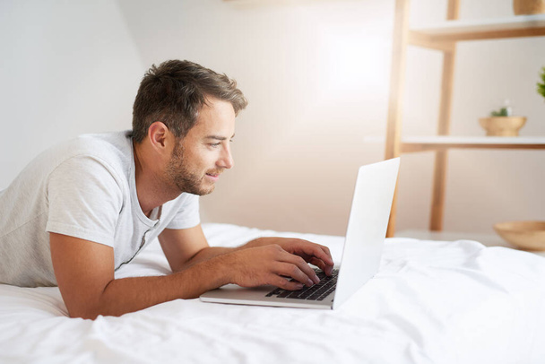 Those A.M social media sessions. Shot of a young man using a laptop on his bed at home. - Foto, Imagem