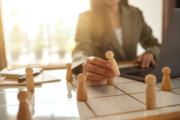 Businesswoman leader choosing wooden people from a group of employees on a planning board - 写真・画像